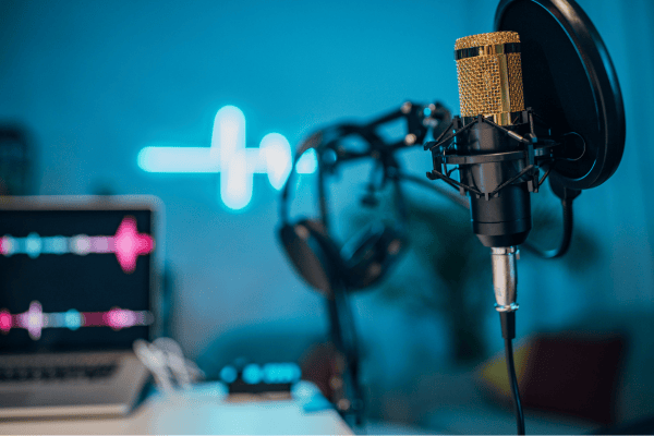 Micro doré, casque et ordinateur avec ondes sonores dans un home studio moderne, ambiance bleutée